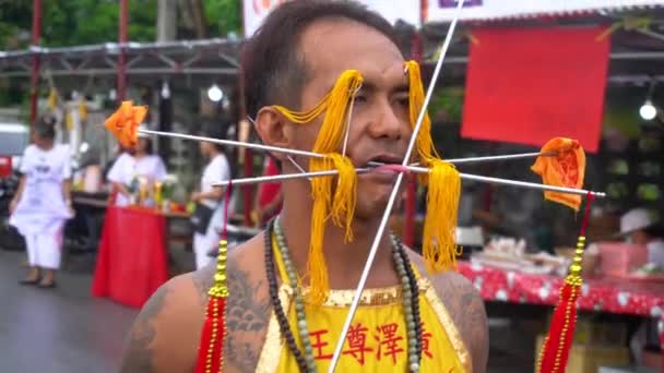 Таиланд, Пхукет, 7 октября 2019 года: Тайский мужчина китайского происхождения с проколотой щекой и языком, проколотый многими металлическими вязальными спицами на ежегодном Пхукетском вегетарианском фестивале — стоковое видео