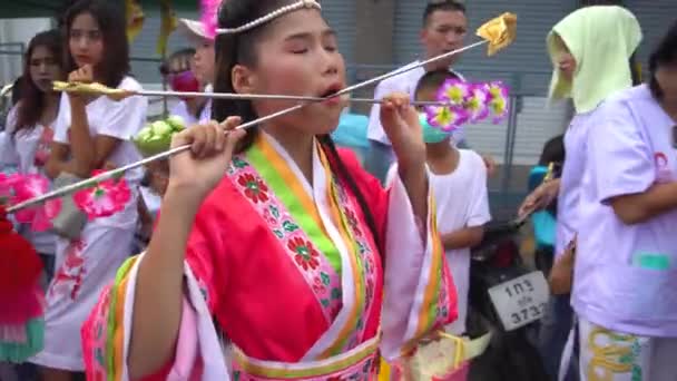 Таїланд, Пхукет, 7 жовтня 2019: Портрет молодої красивої тайської дівчини китайського походження з проколотим металом в'язаною голкою на щоці на честь свята вегетаріанців. — стокове відео