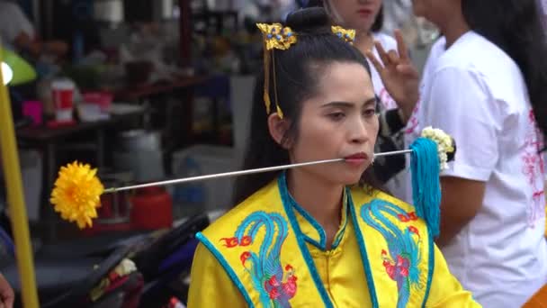 Tailandia, Phuket, 7 de octubre de 2019: Retrato de cierre de la joven chica tailandesa guapa de ascendencia china con una aguja de punto de metal perforado sobre su mejilla en la celebración de un festival de vegetarianos. — Vídeos de Stock