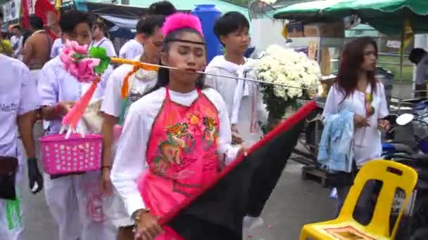 Tailandia, Phuket, 7 de octubre de 2019: Retrato de cierre de la joven chica tailandesa guapa de ascendencia china con una aguja de punto de metal perforado sobre su mejilla en la celebración de un festival de vegetarianos. — Vídeo de stock