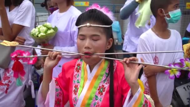 Tailandia, Phuket, 7 de octubre de 2019: Retrato de cierre de la joven chica tailandesa guapa de ascendencia china con una aguja de punto de metal perforado sobre su mejilla en la celebración de un festival de vegetarianos. — Vídeos de Stock