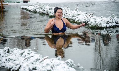 A woman walks into a hole with ice water. Baptized Conducting the rite of consecration of water on the eve of the feast of the Baptism of the Lord. Ukraine. Belogorodka. January 19, 2018