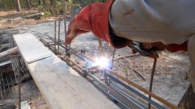 Elektrot kaynak çubukları. Elektrot tutuculu eldivenlerde el kaynakçı. Elektrikli ark kaynağı demiri. Kıvılcımlar yan lara doğru parçalanıyor. Kaynak demir çubuklar. Kiev. Ukrayna. Ekim 19, 2018