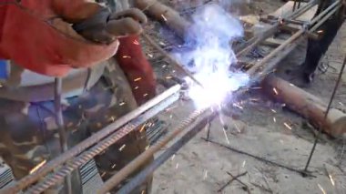 Elektrottan spreyler. Kaynakçı elektrot çubuklar arasında septum kaynak. Elektrot tutuculu eldivenlerde el kaynakçı. Elektrikli ark kaynağı demiri. Kıvılcımlar yan lara doğru parçalanıyor. Kaynak demir çubuklar. Kiev. Ukrayna. Ekim 19, 2018