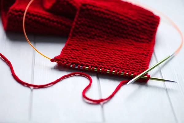 针织。明亮的红领巾，在白色木制背景上用针织针编织 — 图库照片