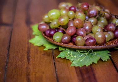 Üzüm ahşap bir masa üzerinde bir kil tabakta. Natürmort pembe muscat üzüm ile.