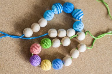 Kolye bir Sling oturan bebek için örme boncuklar ve oyuncaklar yapılmış.