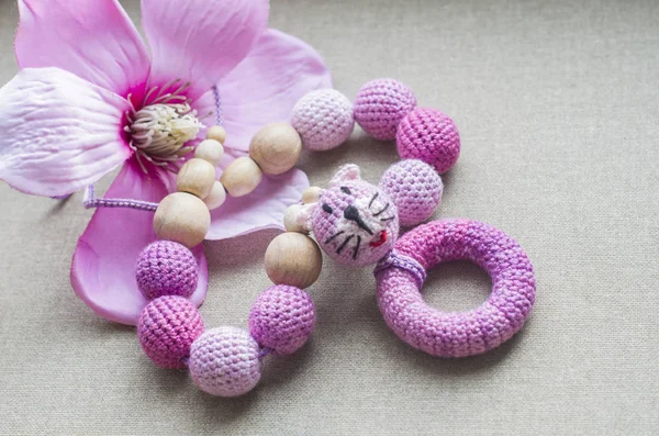 Halsband gjord av stickade pärlor och leksaker för barnet sitter i en sele. — Stockfoto