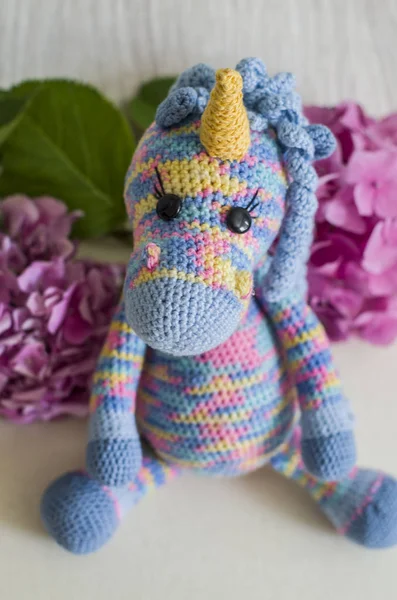 Crocheted unicorn lilac of melange threads are yellow elements.