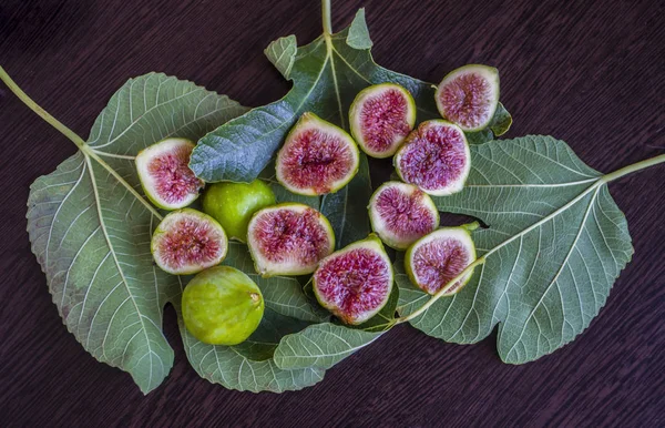 Figues fraîches tranchées sur des feuilles vertes . — Photo