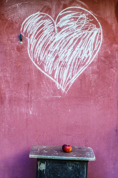 Mela rossa su sgabello e disegno del cuore con gesso . — Foto Stock