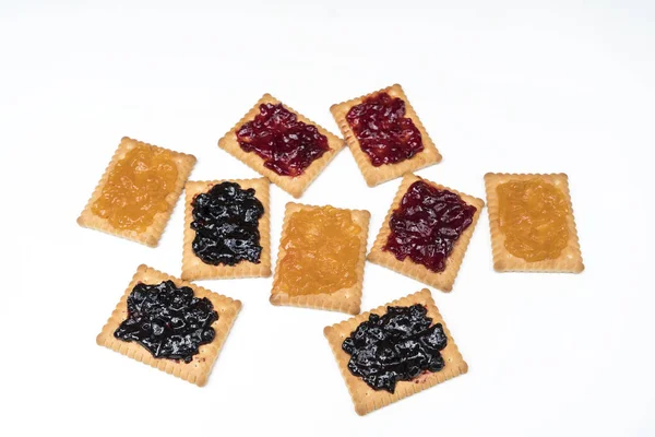 Some dry biscuits with jam on a white surface