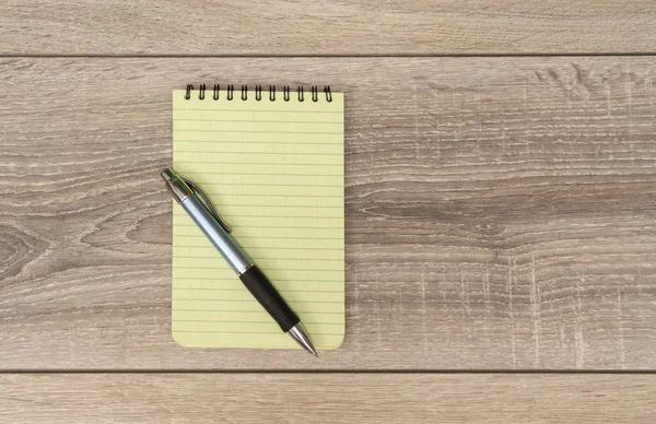 an empty block and a pen on the wooden table