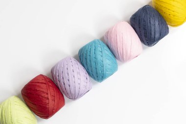 Beyaz yüzeyde renkli rafya topları var.