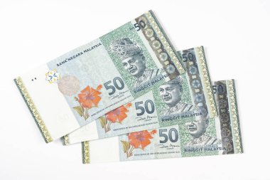 Beyaz bir yüzey üzerinde üç tane 50 Malezya Halkası banknotu