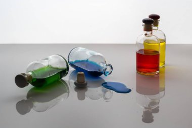 Mavi sıvı sızıntısı tarafından küçük cam şişe beyaz bir yüzeye