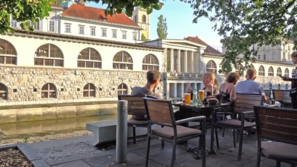 リュブリャナ スロベニア 2019年8月3日市内中心部のリュブリャニカ川の海岸沿いの屋外カフェで人々の姿 — ストック動画