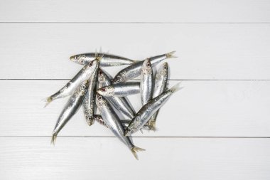 Beyaz ahşap bir masaya dizilmiş sardalyalar.