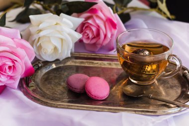 pembe macaroons, vintage gümüş tepsi üzerinde sıcak çay gül arka plan bulanık.