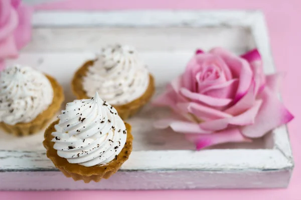 Niedlichen Vanille Cupcakes Auf Vintage Holztablett Mit Rosafarbenen Blumen Hintergrund — Stockfoto