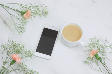 Üstten Görünüm smartphone ve mermer bir tablo çerçeve çiçek içkiyle fincan