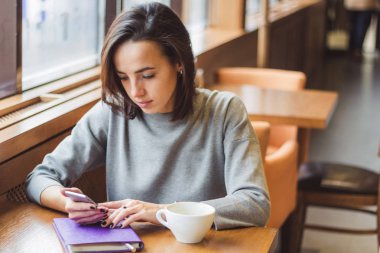 bir günlük ve bir cep telefonu ile çalışma bir kafede bir masada genç güzel esmer