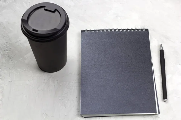 black paper cup of coffee to go black notebook and pen