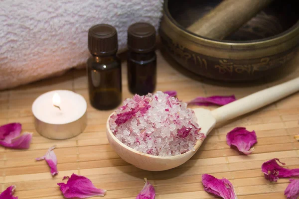 homemade body scrub from sea salt and rose petals and peony, Tibetan bowl,candle,pink towel and aroma oil  on a straw Mat. Spa concept