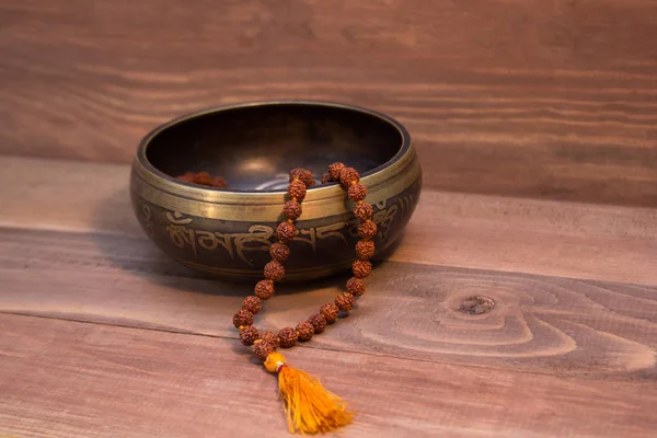singing bowl and Rudraksha on wooden background