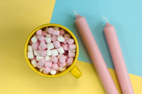 yellow mug with marshmallows and pink candles on a blue and yellow background
