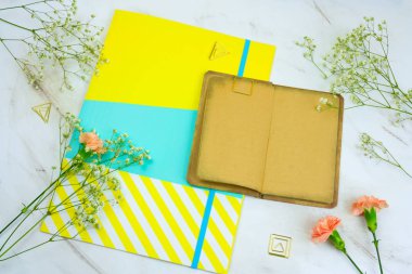 Üstten Görünüm mermer bir zemin üzerine boş çarşafları, brigt kağıt klasör ve çiçeklerle vintage kitap