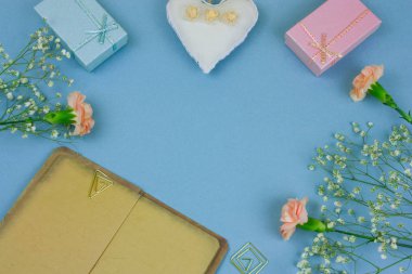 Üstten Görünüm pastel mavi arka plan üzerinde boş çarşafları, hediye kutuları ve çiçeklerle vintage kitap