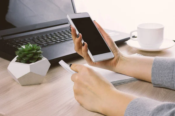 Vrouw Handen Met Smartphone Een Bsckground Van Werkplek Met Laptop — Stockfoto