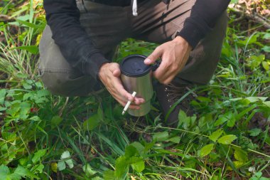 adam traveler sıcak içki ve sigara ormandaki bir kupa ile durma