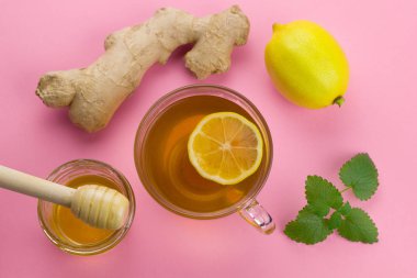 pembe canlı arka planda soğuk içecek alternatif tıp sağlıklı tahta kaşıkla üstten görünüm çay, limon, zencefil, nane ve sıvı bal kavanozu