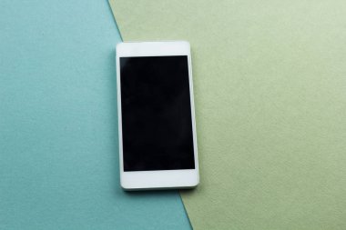 Üstten Görünüm smartphone düz yeşil ve mavi bir arka plan üzerinde yatıyordu