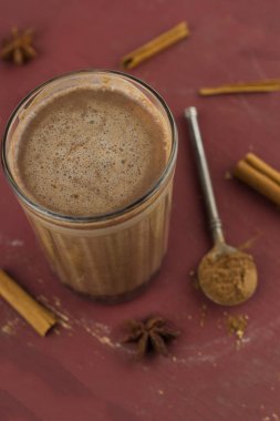 üst görünüm sıcak tatlı baharatlı ev yapımı kakao, tarçın çubukları, anason yıldızları ve kuru kakao tozu kaşığı kahverengi bir berbat ahşap masada