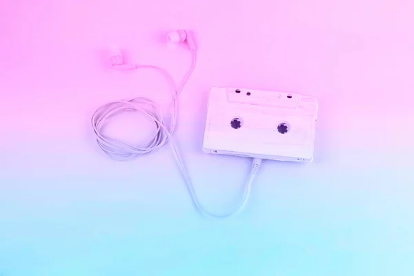 顶部视图音频卡塞特磁带和耳机柔和的蓝色和粉红色渐变色调平躺 — 图库照片