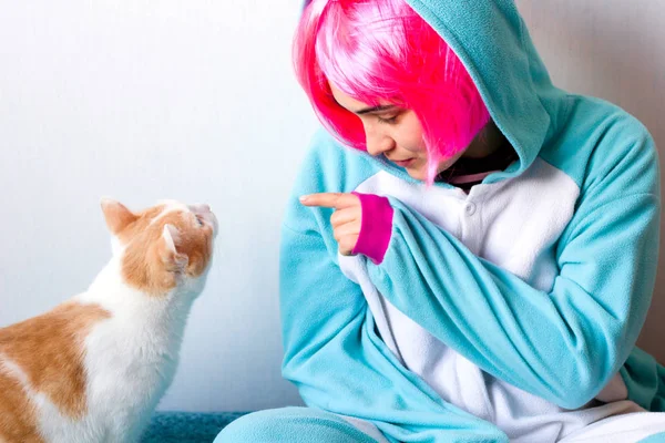 Kadın pembe peruk ve kigurumi tek boynuzlu at kostüm kedi ile oynamak