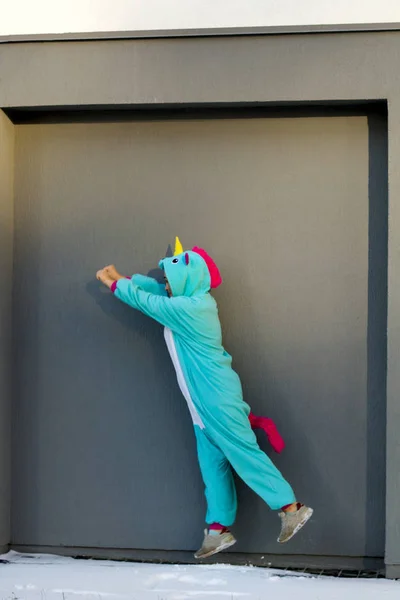 Милая Женщина Костюме Кигуруми Единорога Прыгает Супергерой Против Серой Стены — стоковое фото