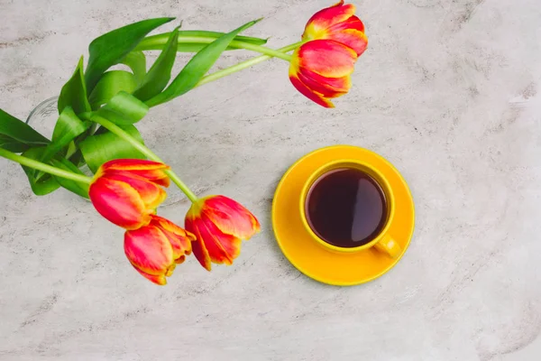 cup of drink  and tulips on marble table, top view