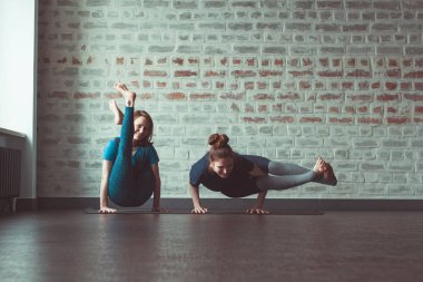 iki güzel beyaz kadın Partner yoga yoga Studio tuğla duvar karşısında yapıyor