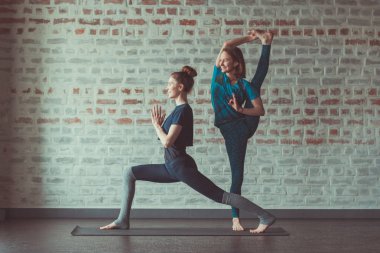iki güzel beyaz kadın Partner yoga yoga Studio tuğla duvar karşısında yapıyor