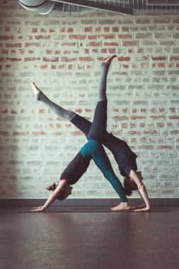 iki güzel beyaz kadın Partner yoga yoga Studio tuğla duvar karşısında yapıyor