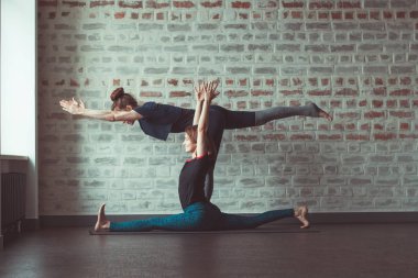 iki güzel beyaz kadın Partner yoga yoga Studio tuğla duvar karşısında yapıyor