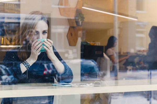 woman in a coffee shop, shot through the glass