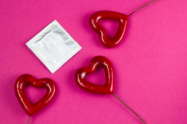top view condom and 3 red hearts pink background clipart