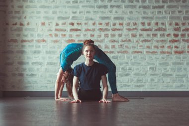 iki güzel beyaz kadın Partner yoga yoga Studio tuğla duvar karşısında yapıyor