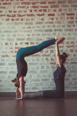 iki güzel beyaz kadın Partner yoga yoga Studio tuğla duvar karşısında yapıyor