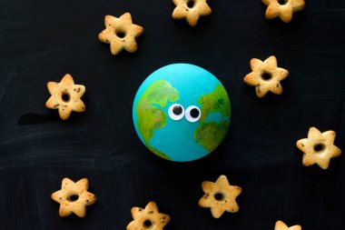 Top görünüm el yapımı model dünya gezegeni komik göz ve kurabiye ile yıldızlar şeklinde kara tahta, uzay ve astronomi konsepti